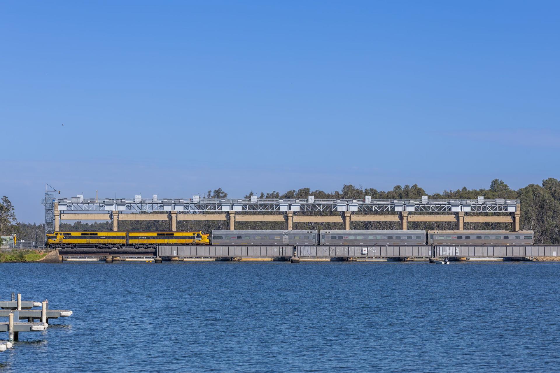 Interstate locomotives hauling a passenger train across a bridge in Australia